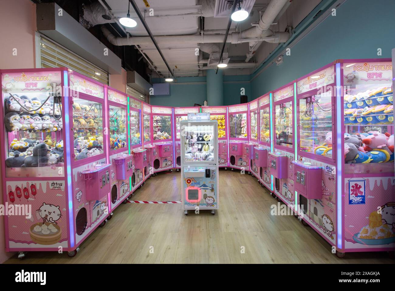 Geräumiger rosafarbener Laden mit Klauenmaschinen. Jede Maschine enthält verschiedene Arten von niedlichen Plushie-Preisen, die der Benutzer anfangen kann, um ihn zu Hause zu gewinnen. Singapur. Stockfoto