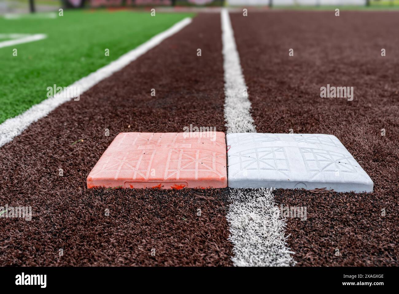 Blick auf High School Kunstrasen Softball Feld erste Basis mit zweiten orange Sicherheitsbasis, Blick in Richtung Heimat Platte. Stockfoto