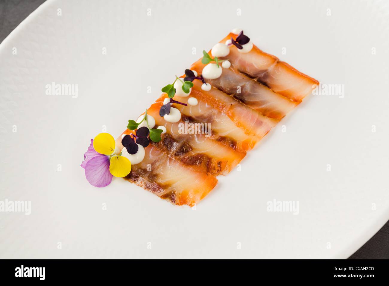 Geräucherter Fisch, Pastrami oder Speck auf einem weißen Porzellanteller Stockfoto