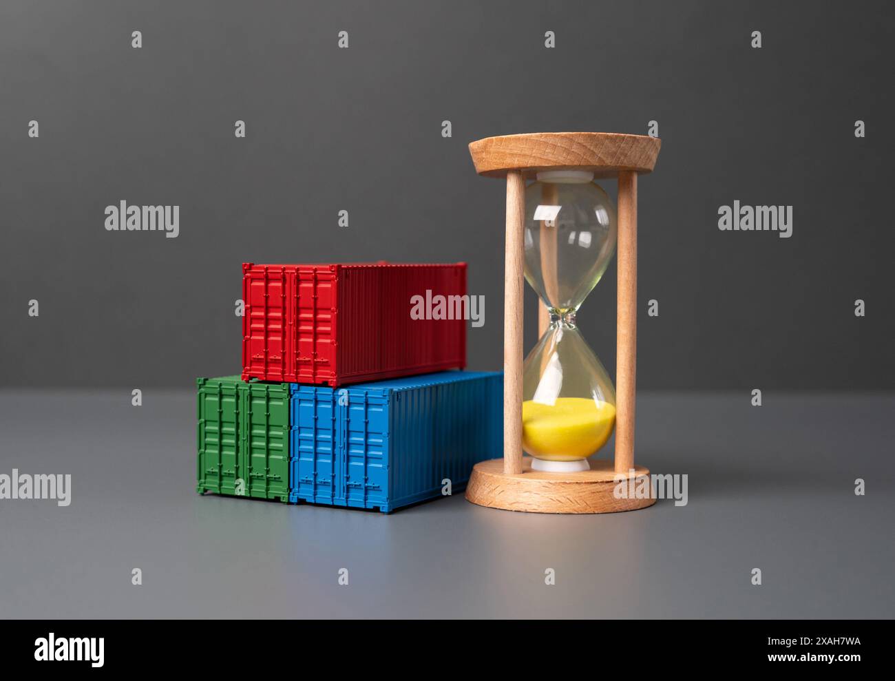 Versandbehälter und Sanduhr. Fracht- und Versandkosten. Lieferdauer. Logistik und Transport von gewerblicher Fracht. Containerverleih. Stockfoto