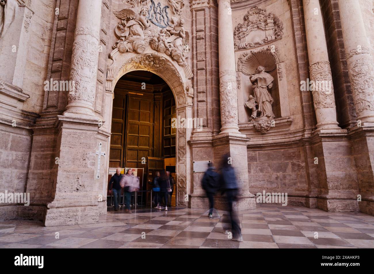 Die Besucher gehen am kunstvollen Eingang der Kathedrale von Valencia vorbei, wo sie ihre komplizierten Steinschnitzereien und die historische Architektur bewundern Stockfoto