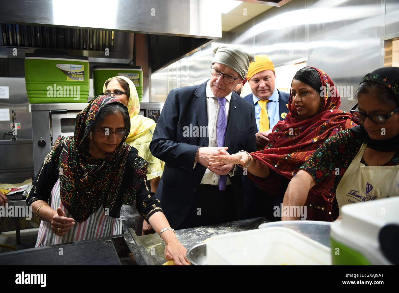 SNP-Chef John Swinney und Parlamentskandidat Chris Stephens werden die Küchen während seines Besuchs in Glasgow Gurdwara gezeigt, während er sich auf dem Wahlkampfpfad der Wahl befindet. Bilddatum: Freitag, 7. Juni 2024. Stockfoto