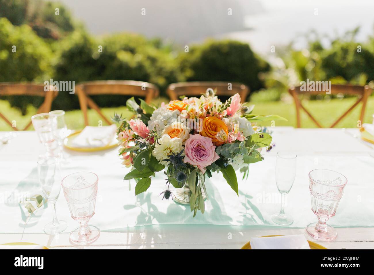 Farbenfrohe Tischblumen-Anordnung für die Hochzeit mit pinkfarbenen Gläsern Stockfoto