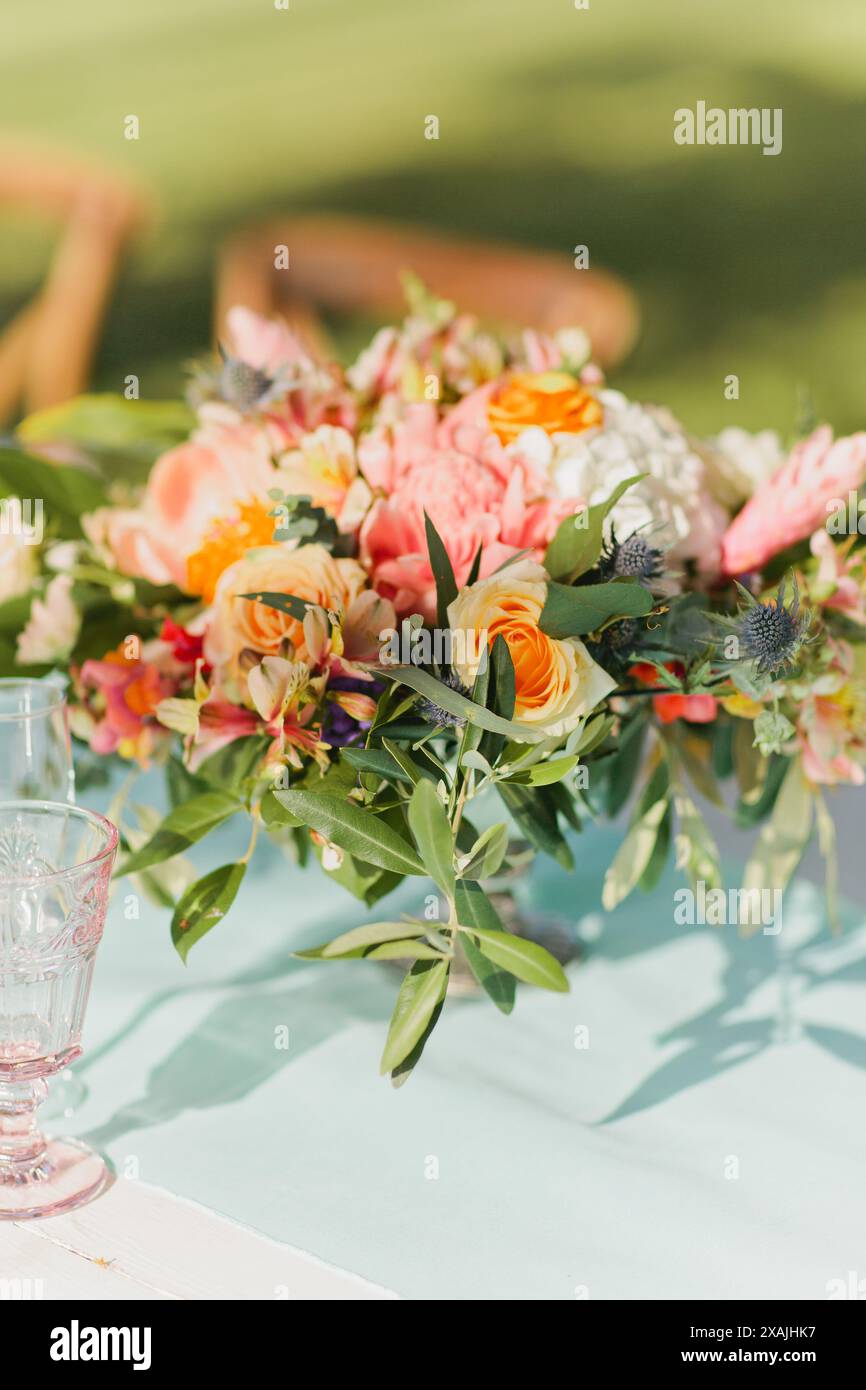 Farbenfrohe Tischblumen-Anordnung für die Hochzeit mit pinkfarbenen Gläsern Stockfoto