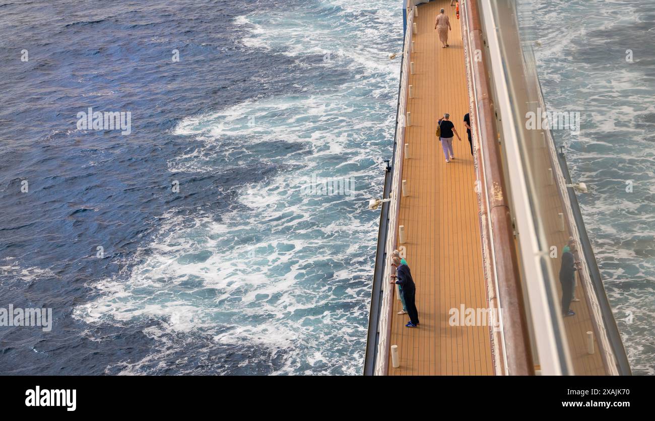 Ältere, reife Kreuzfahrtpassagiere, die einen zügigen Spaziergang in der sauberen Meeresluft rund um ein Promenadendeck machen Stockfoto