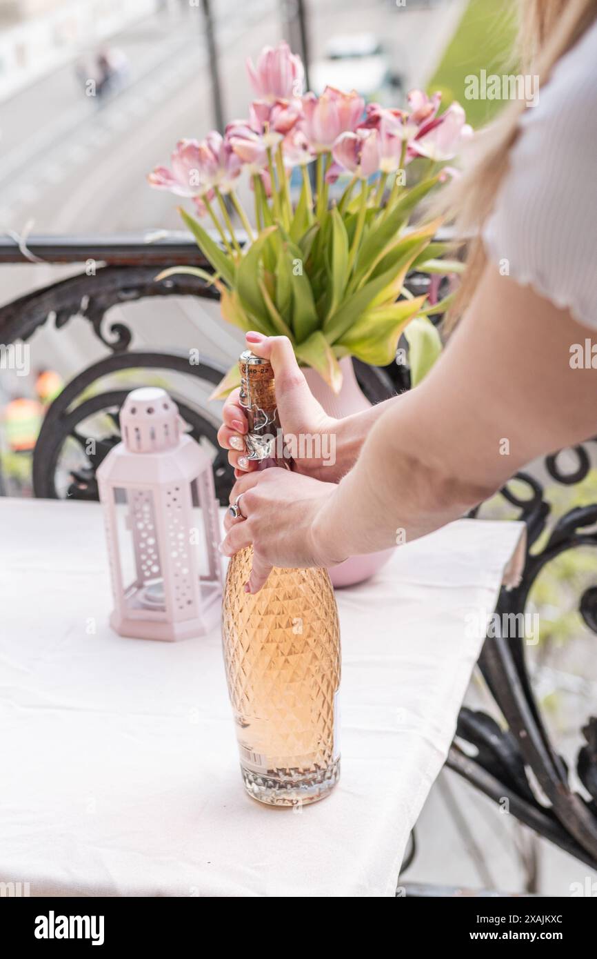 Ein Mädchen, das eine Flasche Rosenwein auf einem Balkon in Budapest öffnet Stockfoto
