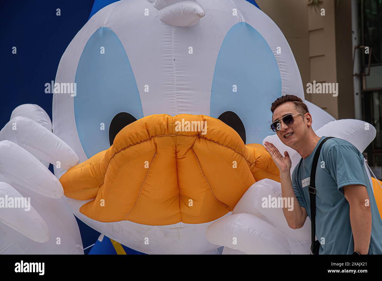 Bangkok, Thailand. Juni 2024. Ein Mann posiert für ein Foto neben einem Ballon von Donald Duck während des 90. Jahrestages der Disney-Figur „Donald Duck“ im Einkaufszentrum Siam Paragon. Donald Duck ist eine Zeichentrickfigur von Walt Disney, die 1934 das Filmdebüt gab. (Foto: Peerapon Boonyakiat/SOPA Images/SIPA USA) Credit: SIPA USA/Alamy Live News Stockfoto