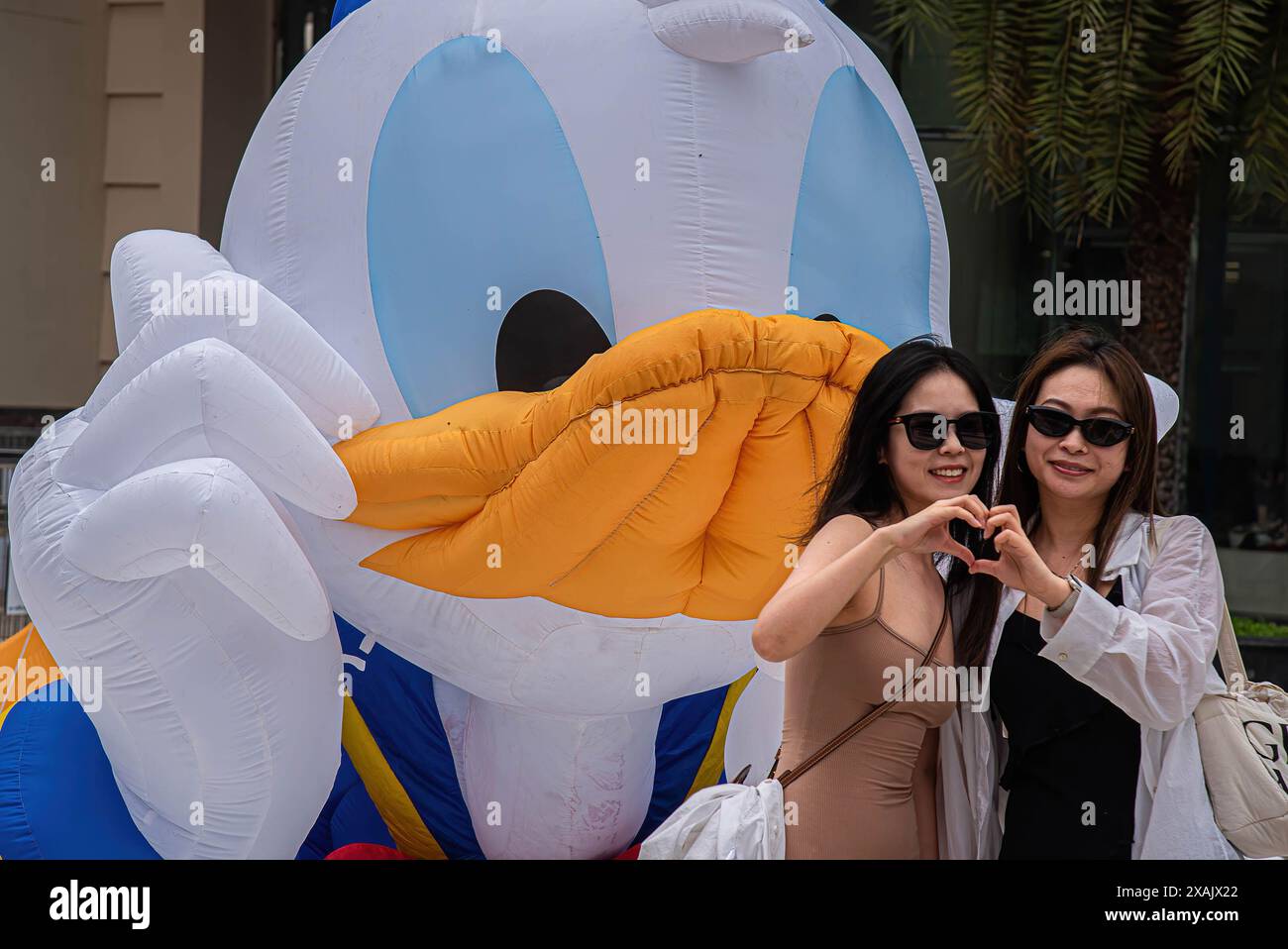 Bangkok, Thailand. Juni 2024. Frauen posieren für ein Foto vor einem Ballon von Donald Duck während des 90. Jubiläums der Disney-Figur „Donald Duck“ im Einkaufszentrum Siam Paragon. Donald Duck ist eine Zeichentrickfigur von Walt Disney, die 1934 das Filmdebüt gab. (Foto: Peerapon Boonyakiat/SOPA Images/SIPA USA) Credit: SIPA USA/Alamy Live News Stockfoto