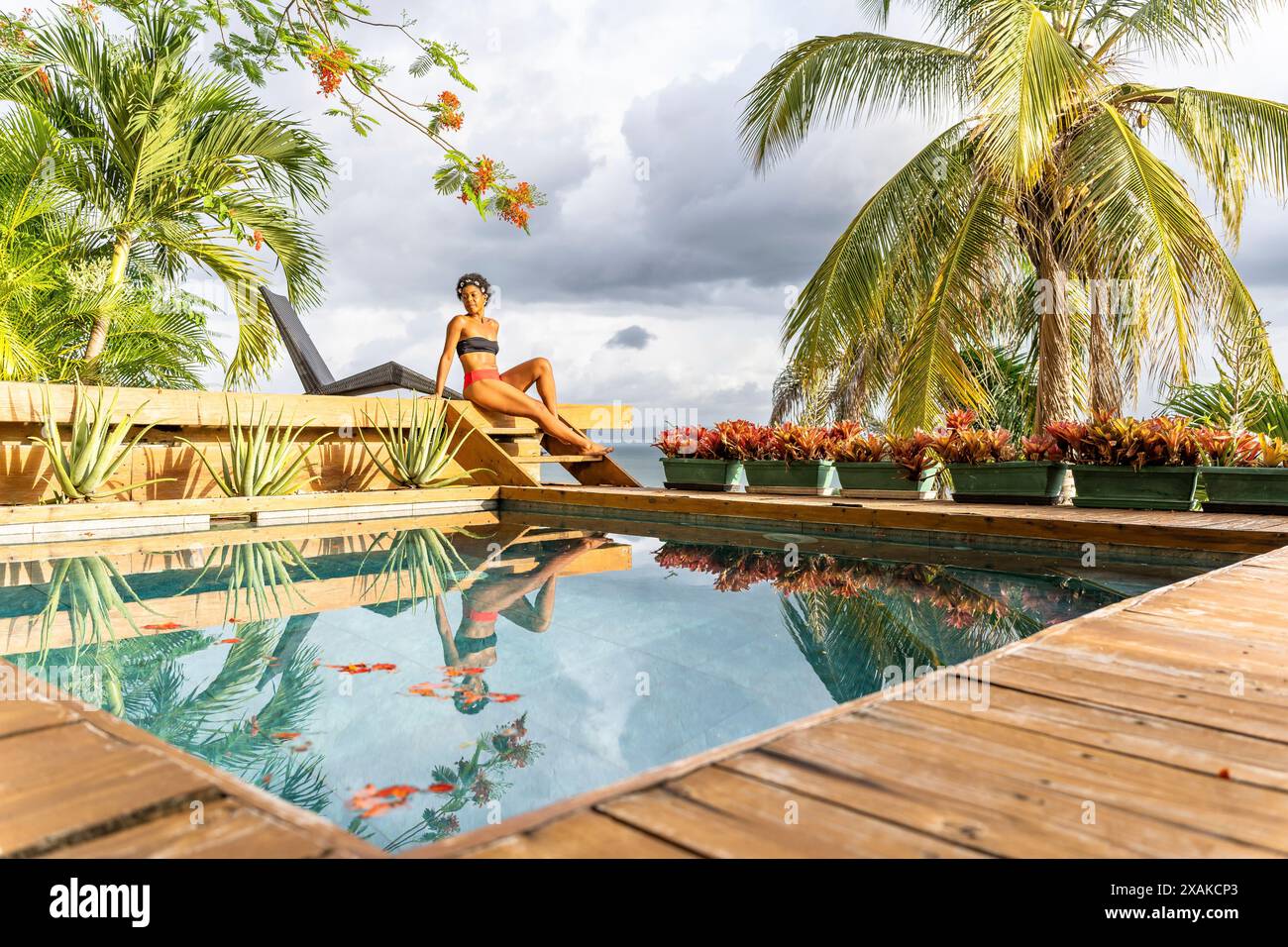 Nordamerika, Karibik, Hispaniola Island, Dominikanische Republik, Samana-Halbinsel, Sanchez, Jardines La Loma, dunkelhäutige Latina im Bikini, die neben dem Pool sitzt Stockfoto