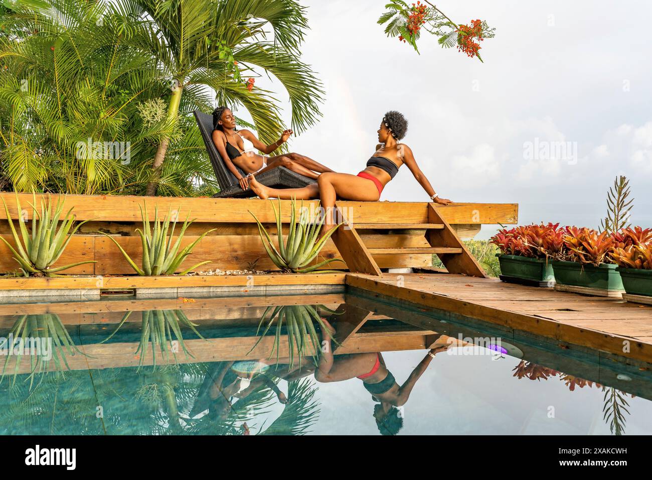 Nordamerika, Karibik, Hispaniola Island, Dominikanische Republik, Samana-Halbinsel, Sanchez, Jardines La Loma, zwei hübsche dunkelhäutige Latinas liegen neben dem Pool und unterhalten sich Stockfoto