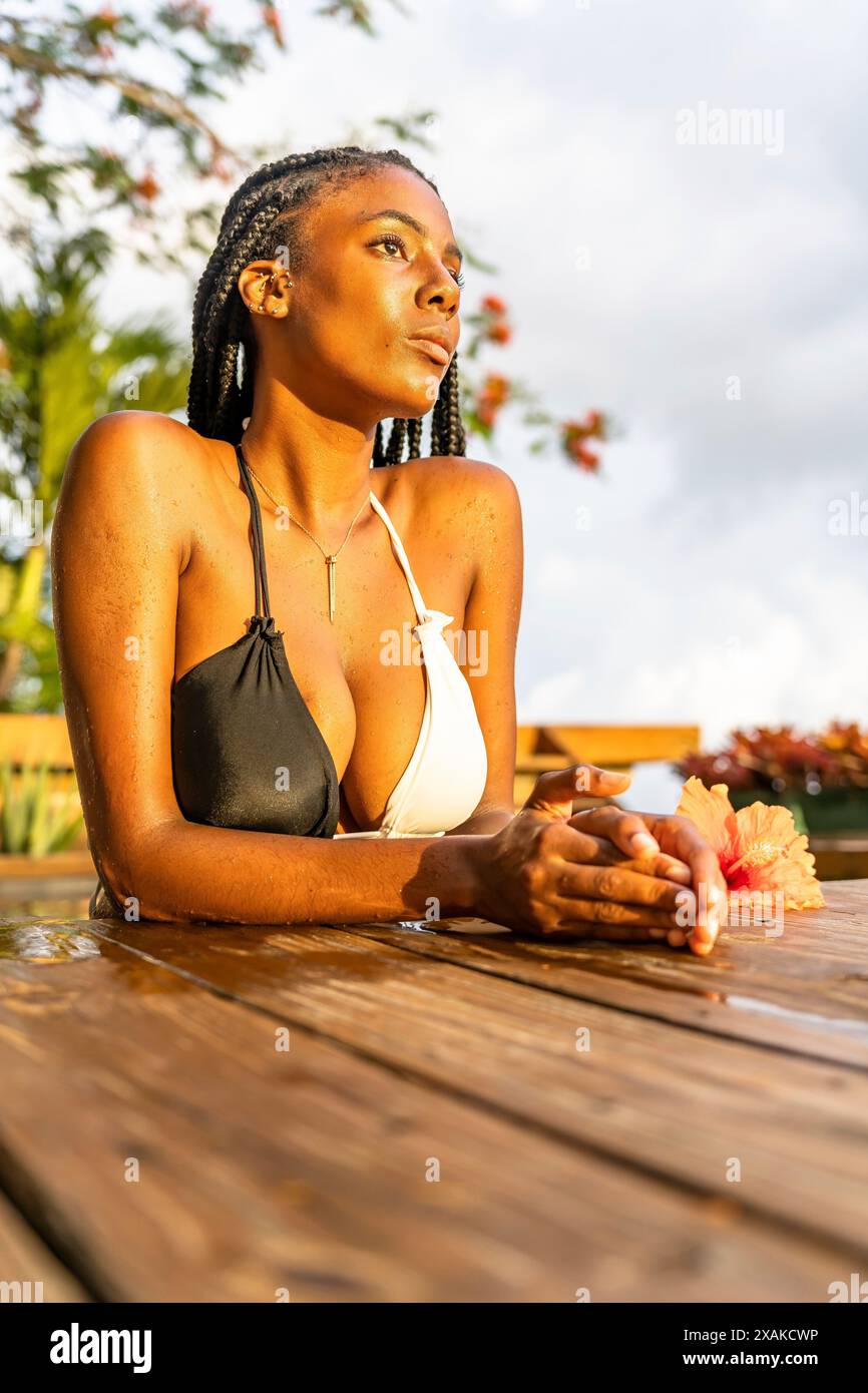 Nordamerika, Karibik, Hispaniola Island, Dominikanische Republik, Samana-Halbinsel, Sanchez, Jardines La Loma, dunkelhäutige Latina lehnt sich an den Rand eines Pools und blickt in die Ferne Stockfoto