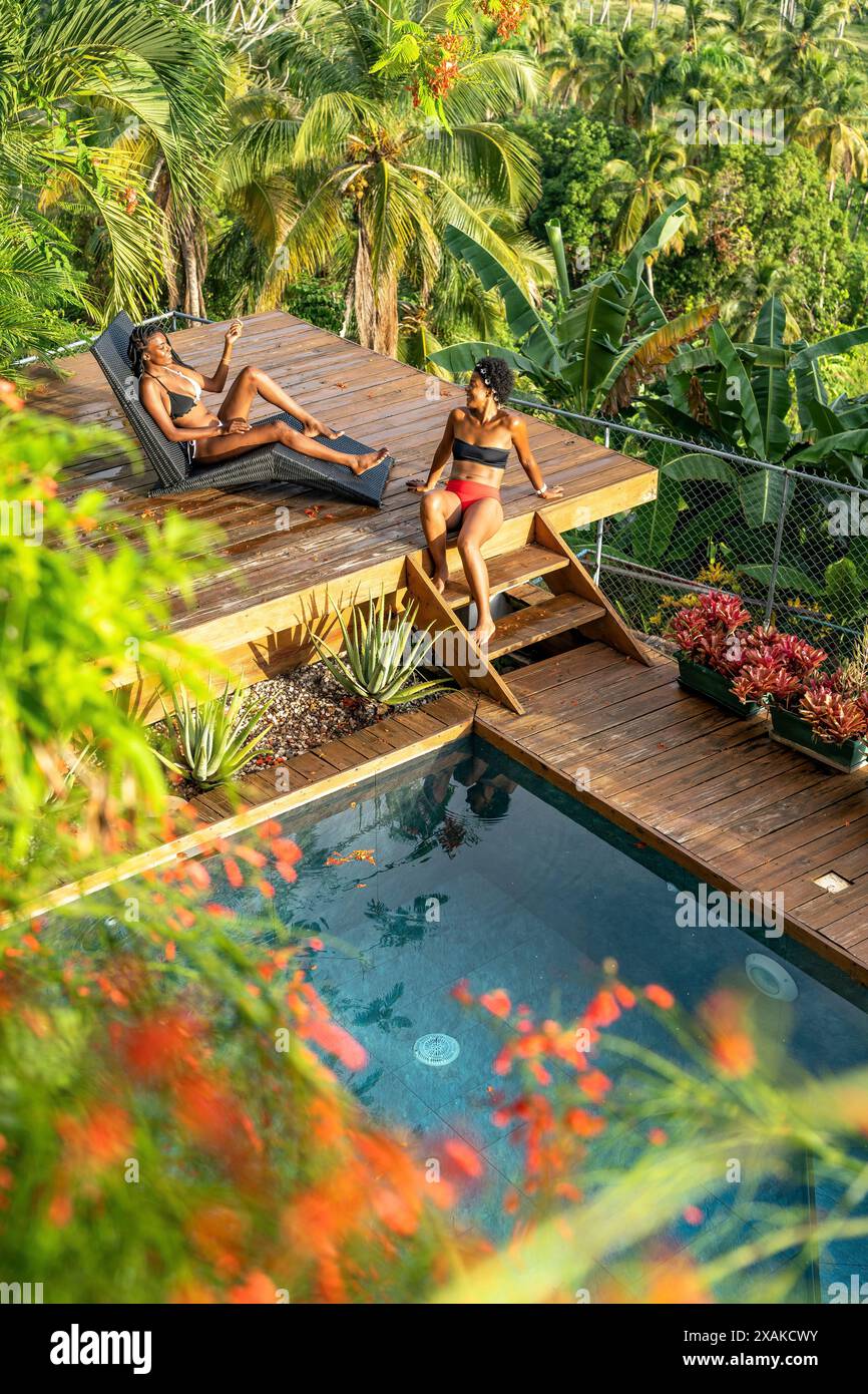 Nordamerika, Karibik, Hispaniola Island, Dominikanische Republik, Samana-Halbinsel, Sanchez, Jardines La Loma, zwei attraktive dunkelhäutige Latinas, die sich am Pool unterhalten Stockfoto