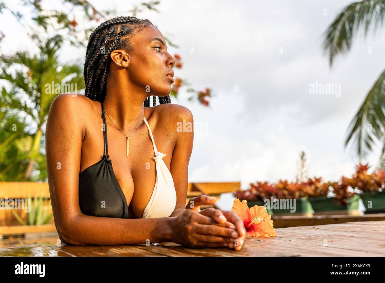 Nordamerika, Karibik, Hispaniola Island, Dominikanische Republik, Samana-Halbinsel, Sanchez, Jardines La Loma, dunkelhäutige Latina lehnt sich an den Rand eines Pools und blickt in die Ferne Stockfoto