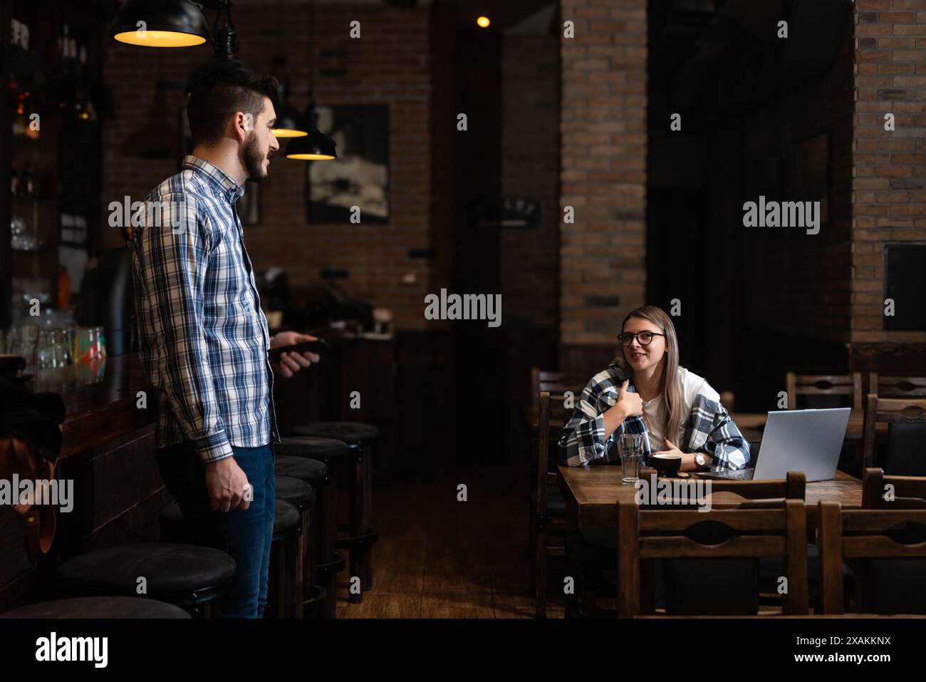 Zwei junge Leute, Mann und Frau, Pub-Besitzer, arbeiten in ihrer Cafeteria, putzen und kalkulieren vor der Öffnungszeit. Mann und Frau arbeiten im Kaffee Stockfoto