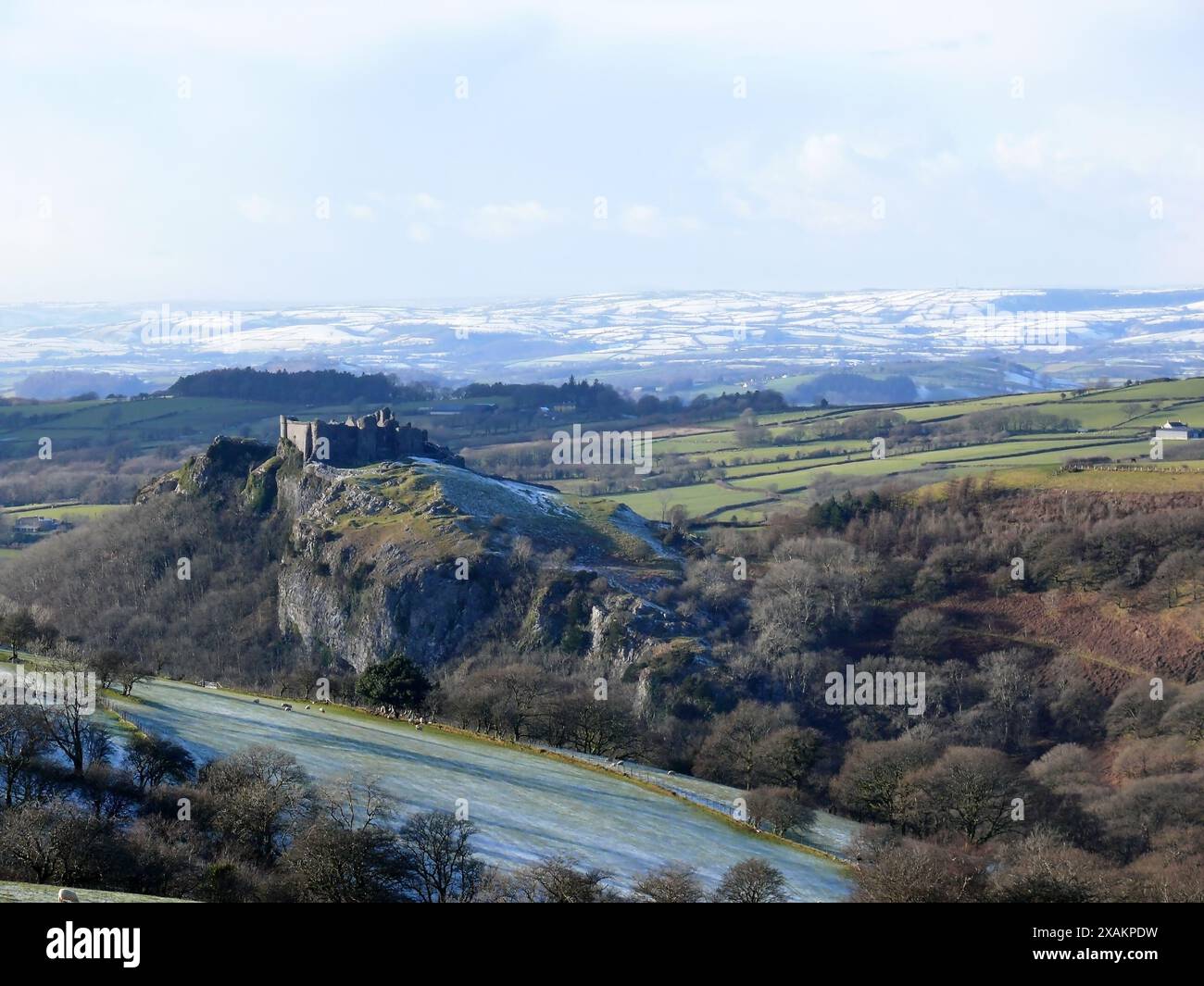 Die Ruine der Burg Carreg Cennen steht auf Kalksteinabstieg mit den schneebedeckten Hügeln von Camarthenshire im Hintergrund. Stockfoto