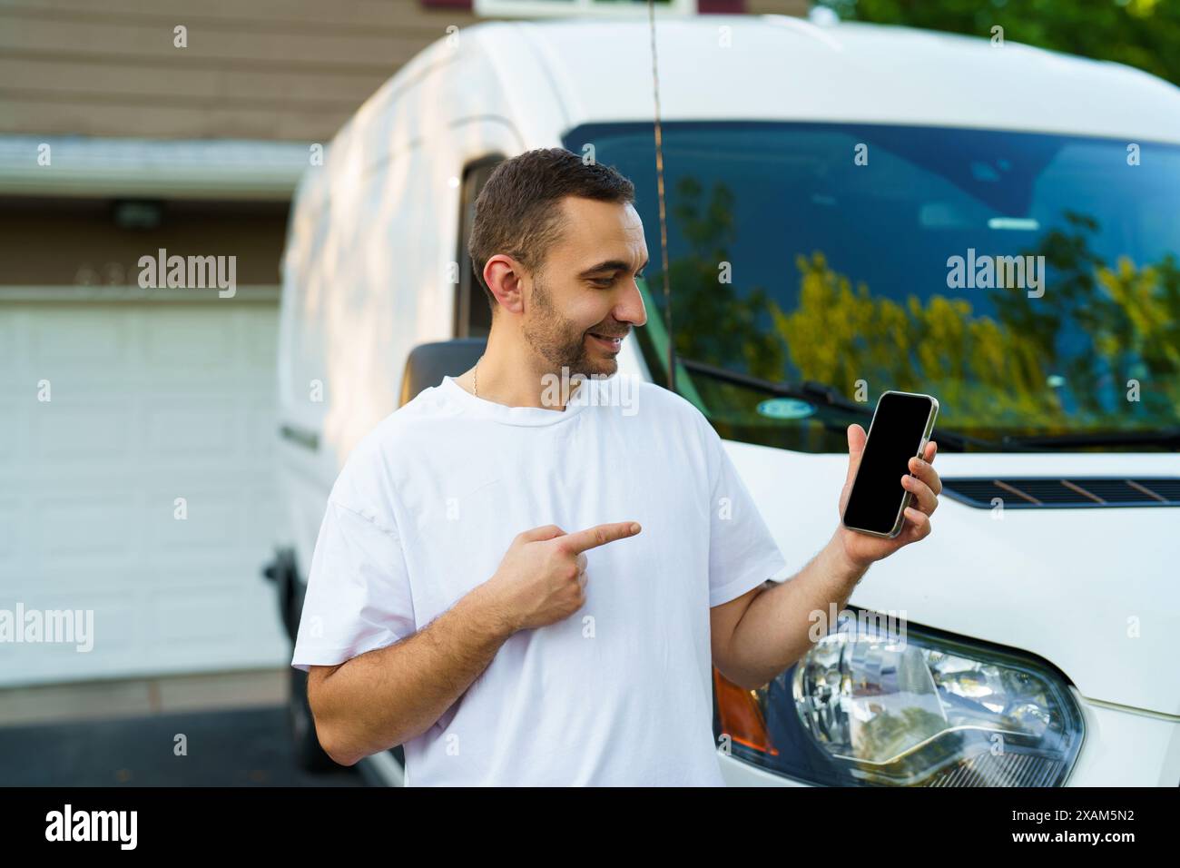 Der junge Mann zeigte einen leeren Bildschirm des Smartphones vor den Van Stockfoto