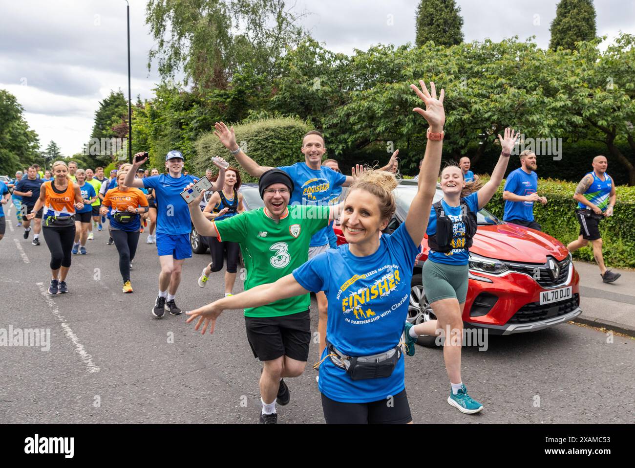 Leeds, Großbritannien. JUNI 2024. Gruppe mit erhobenen Armen sieht vor der Kamera aus, während Läufer eine 7-km-Route, geformt wie ein Nashorn, durch die Straßen von Moor Town zu Ehren der Leeds Rhinos-Legende Nummer 7 Rob Burrow, WHO starb am Sonntag im Alter von 41 Jahren nach einem über 4-jährigen Kampf mit der Motoneurone Disease (MND). Credit Milo Chandler/Alamy Live News Stockfoto