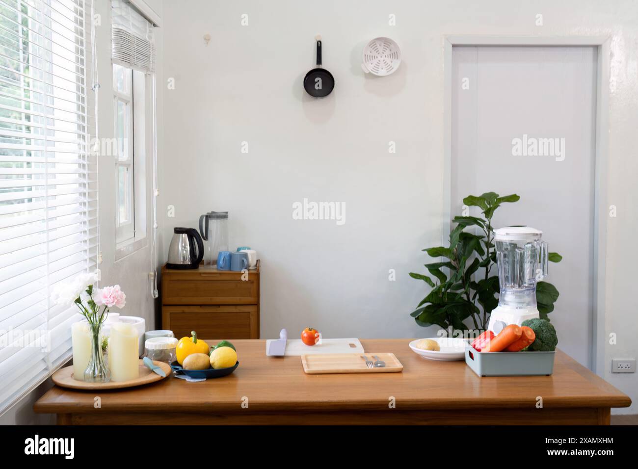 Gepflegte Kücheneinrichtung mit Gemüse und Mixer auf der Theke. Konzept der Hausmannskost und gesunder Lebensstil Stockfoto