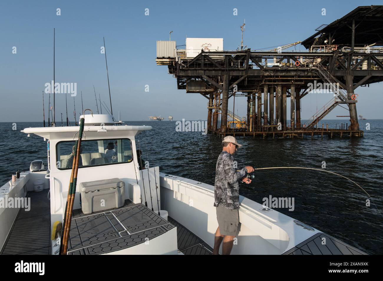 Ein Angler fischt Köderfische, während er von Offshore-Ölplattformen im Golf von Mexiko in der Nähe von Venedig, Louisiana, umgeben ist. Stockfoto