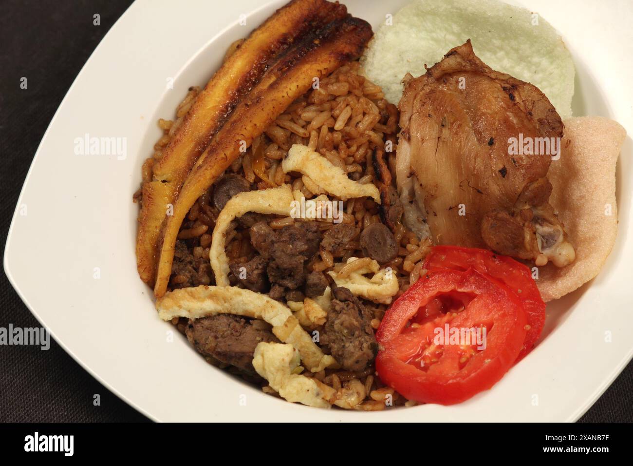 Teller mit köstlichem Nasi-Goreng, gebratenem Krupuk-Kochbananen, Ei, Tomatenscheiben und Hühnerleber-Sambal. Stockfoto