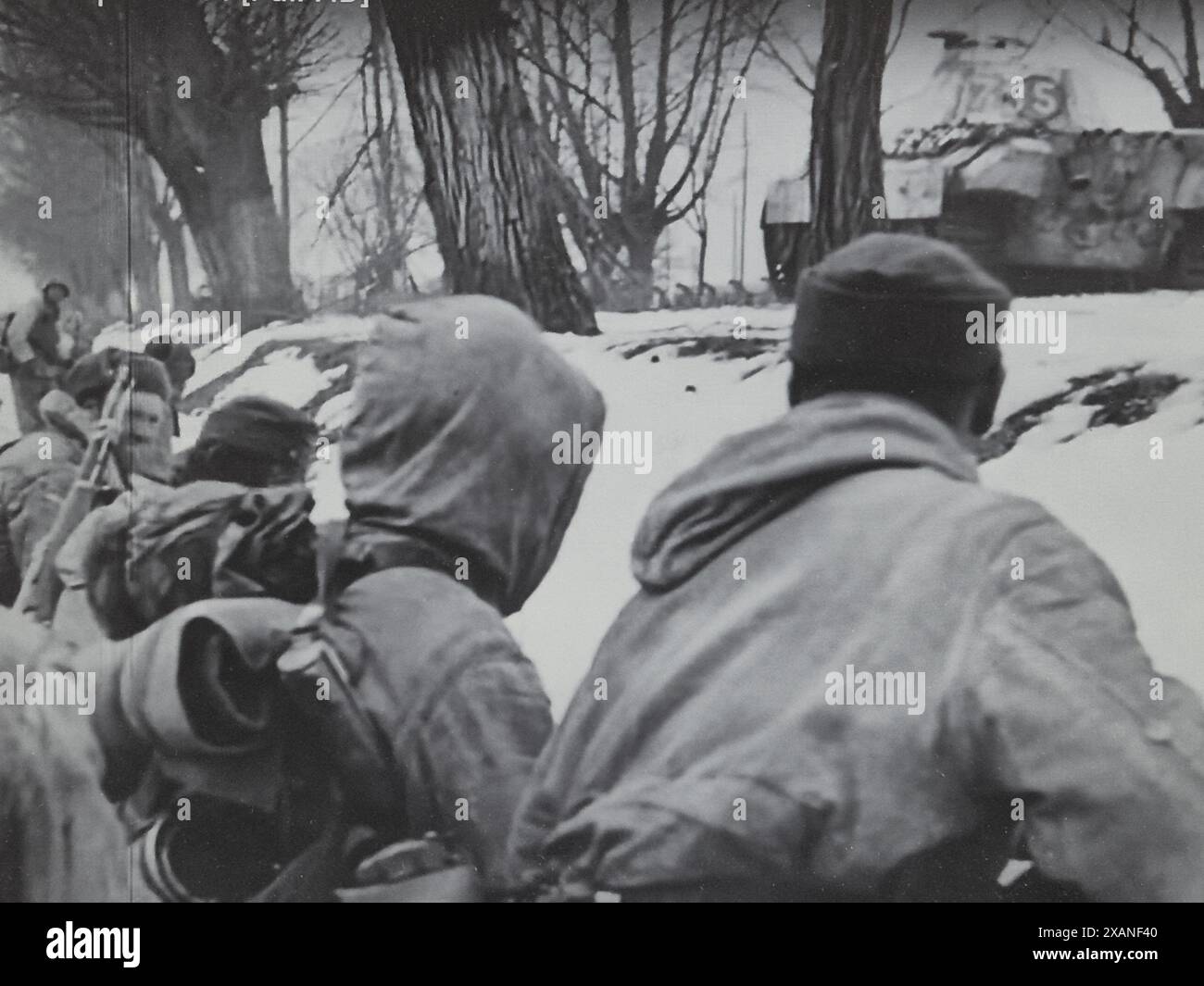 2. Weltkrieg zwei deutsche B&W-Truppen erobern Deckung in einem Straßengraben, während ein Pantherpanzer den Feind angreift Stockfoto