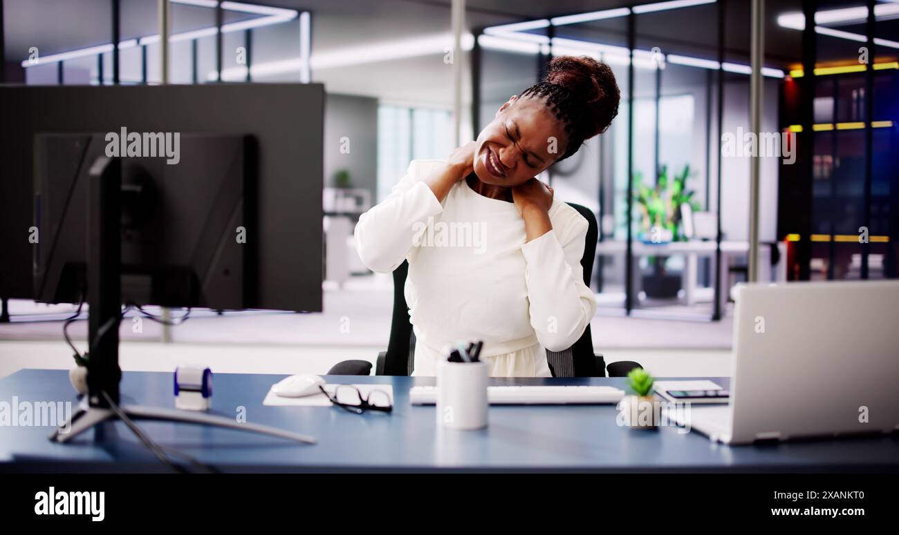 Verbesserung des Wohlbefindens am Arbeitsplatz: Afroamerikanische Frau leidet unter schlechter Ergonomie im Büro, was sich auf Produktivität und körperliche Gesundheit auswirkt Stockfoto