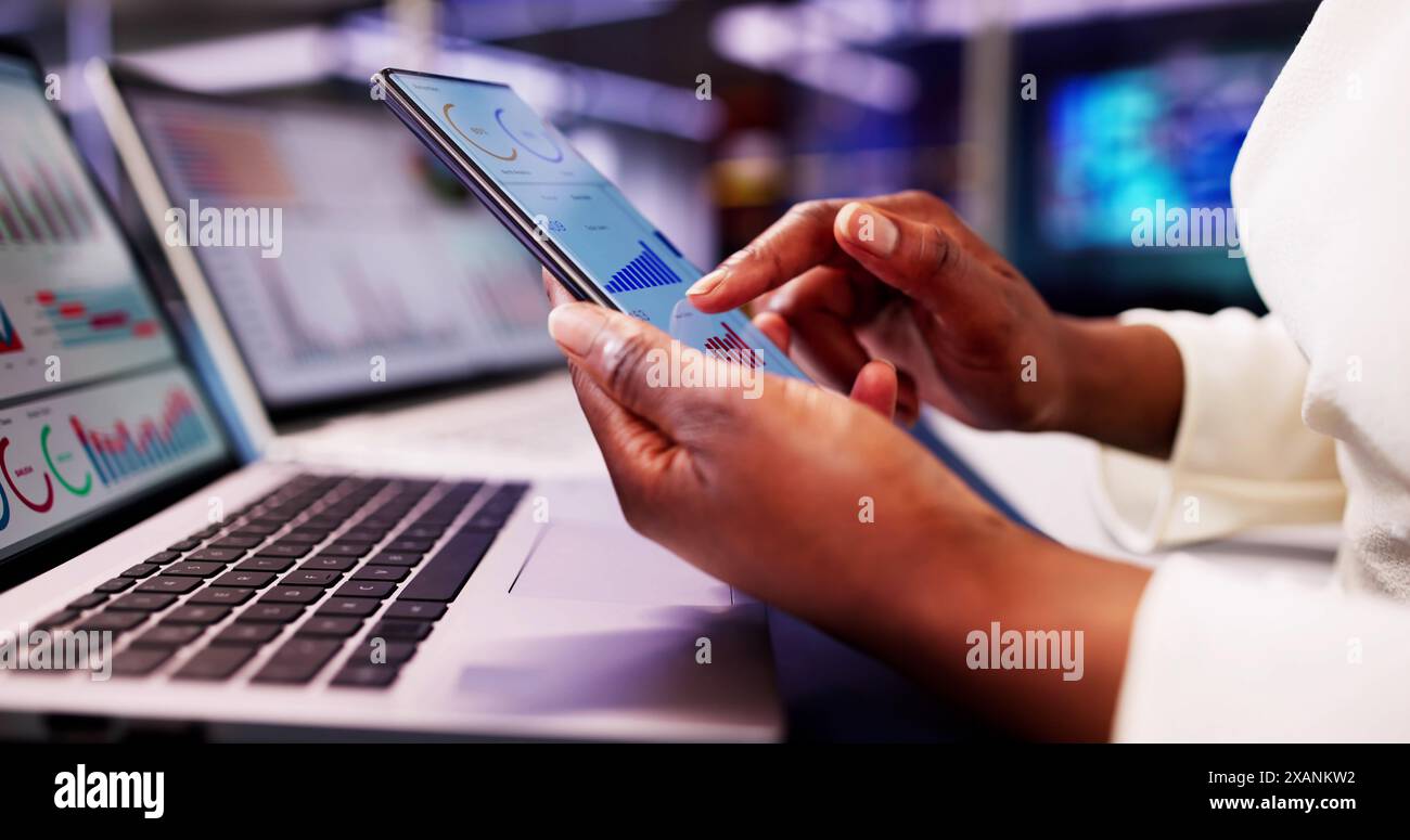 Die afrikanische Finanzberaterin verwendet ein KPI-Dashboard mit Analysediagrammen, um Börsentrends auf ihrem Laptop zu überwachen. Stockfoto