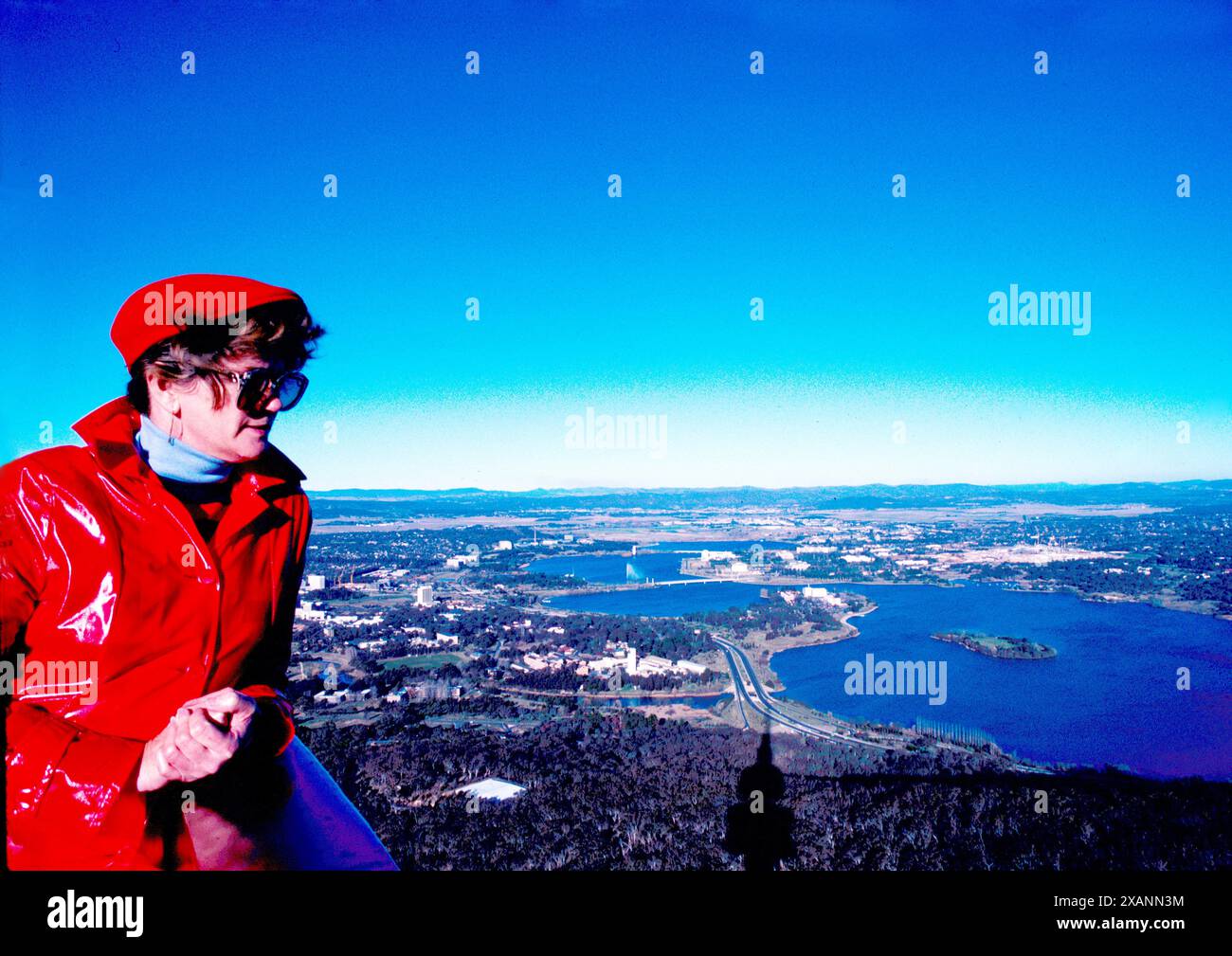 Tourist in rotem Regenmantel mit Blick über den Lake Burley Griffin in Canberra vom Black Mountain Tower Stockfoto