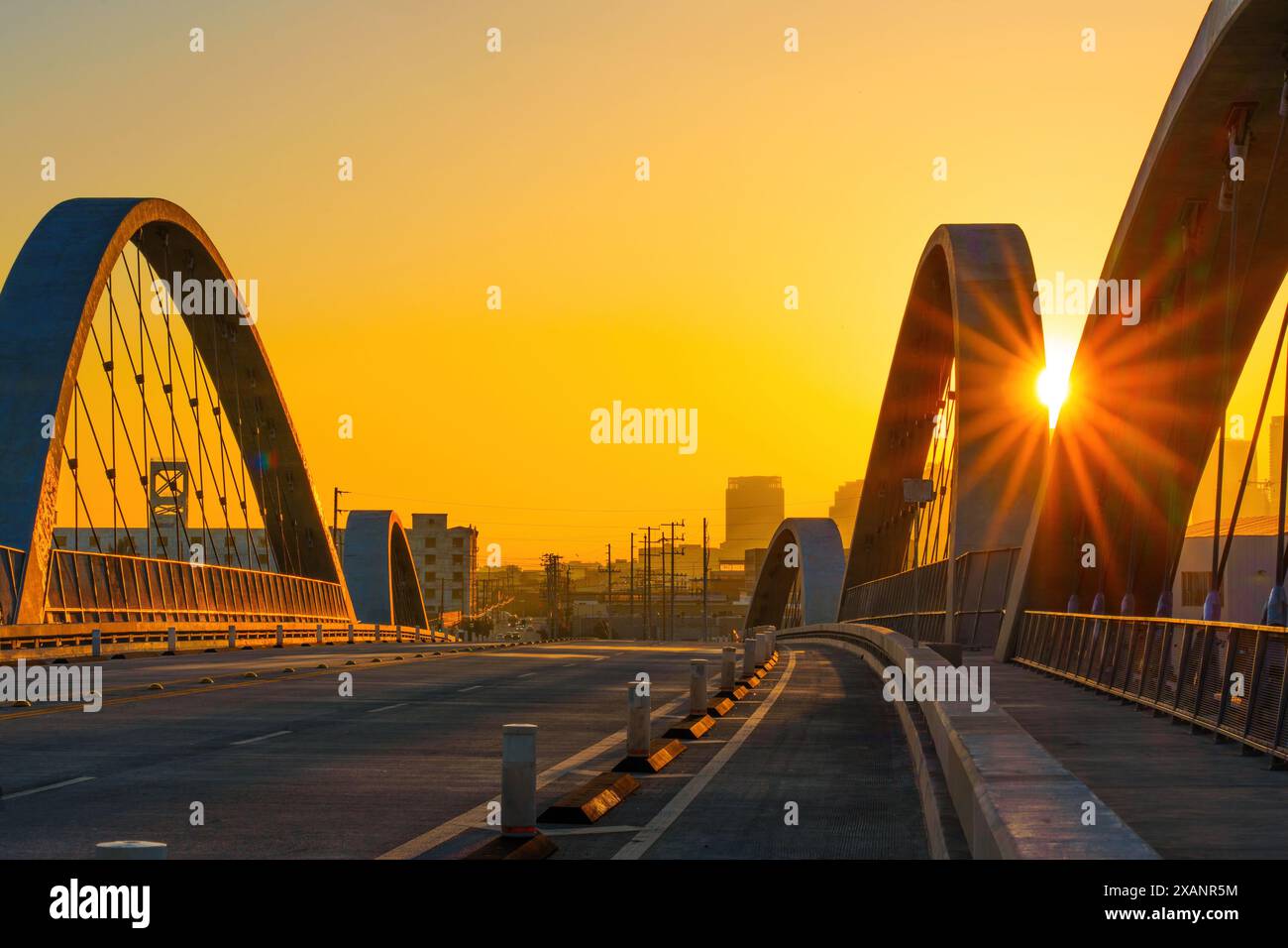 Majestätische Bögen der 6th Street Bridge in Los Angeles im goldenen Licht der untergehenden Sonne getaucht, mit einer atemberaubenden Kulisse aus der Stadt. Stockfoto