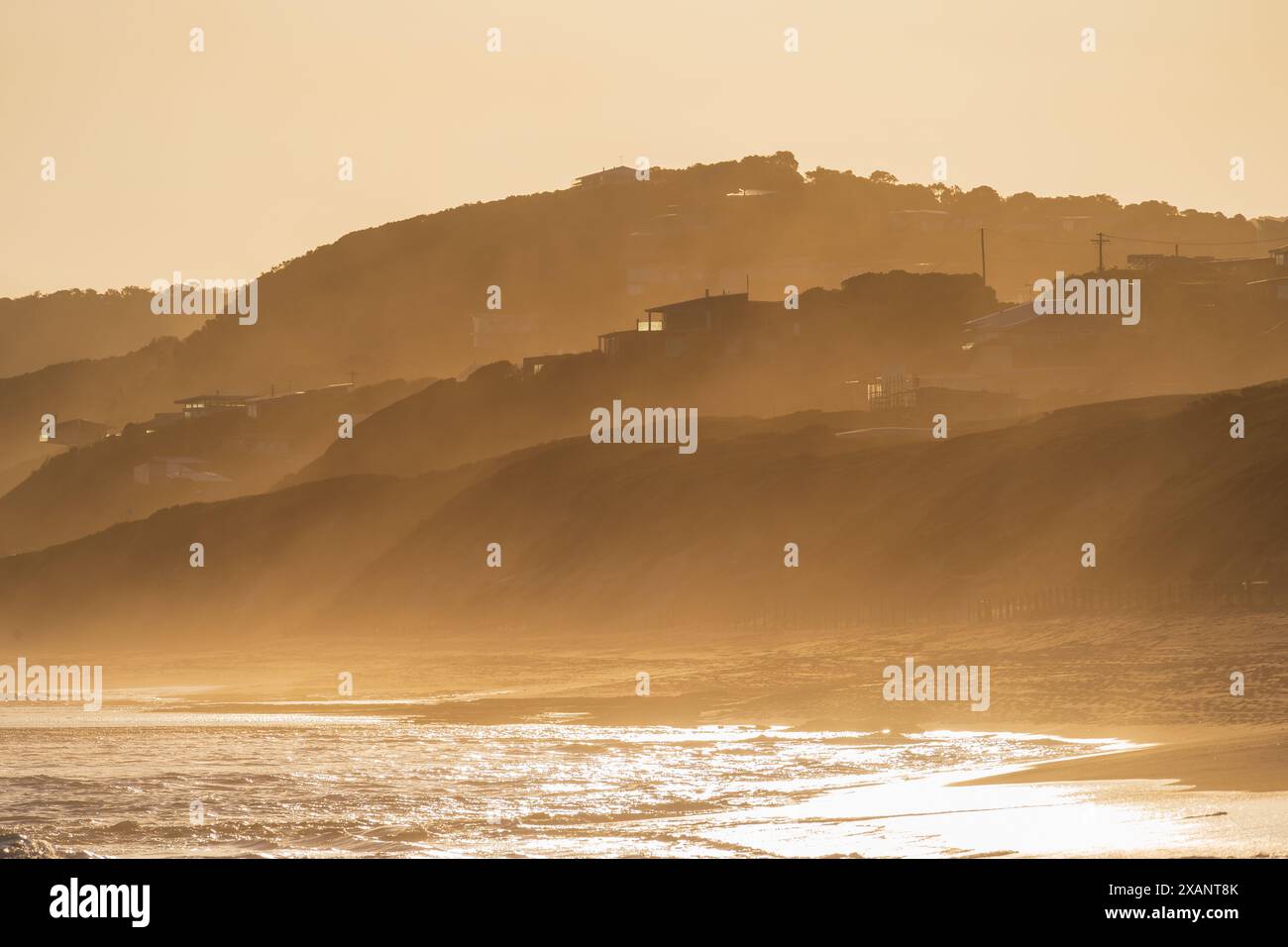 Bei Fairhaven an der Great Ocean Road in Victoria, Australien, liegt der Nebel aus der Ferne über einer hügeligen Küste im goldenen Licht Stockfoto