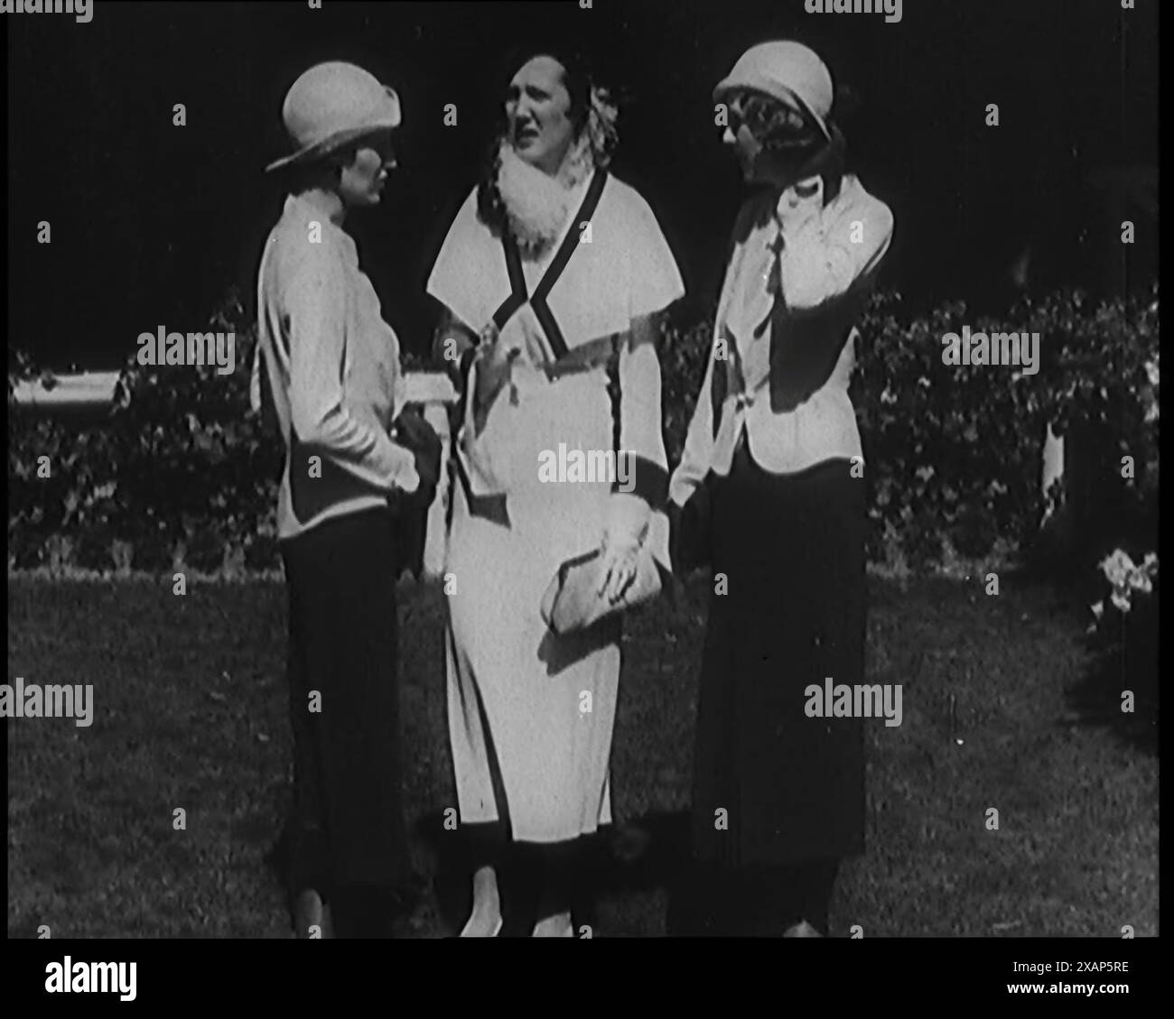 Eine Gruppe von drei weiblichen Zivilisten in modischer Kleidung, stehend in einem Garten, 1929. „Sie sagen mir, dass viele der Mode dieser Zeit wieder da sind“. Aus „Time to Remember – 1929 The Time of the House at Bognor“ – Reel 1; ein Dokumentarfilm über die Welt im Jahr 1929. Krankheit von König Georg V. &amp; wirtschaftliche Depression. Stockfoto