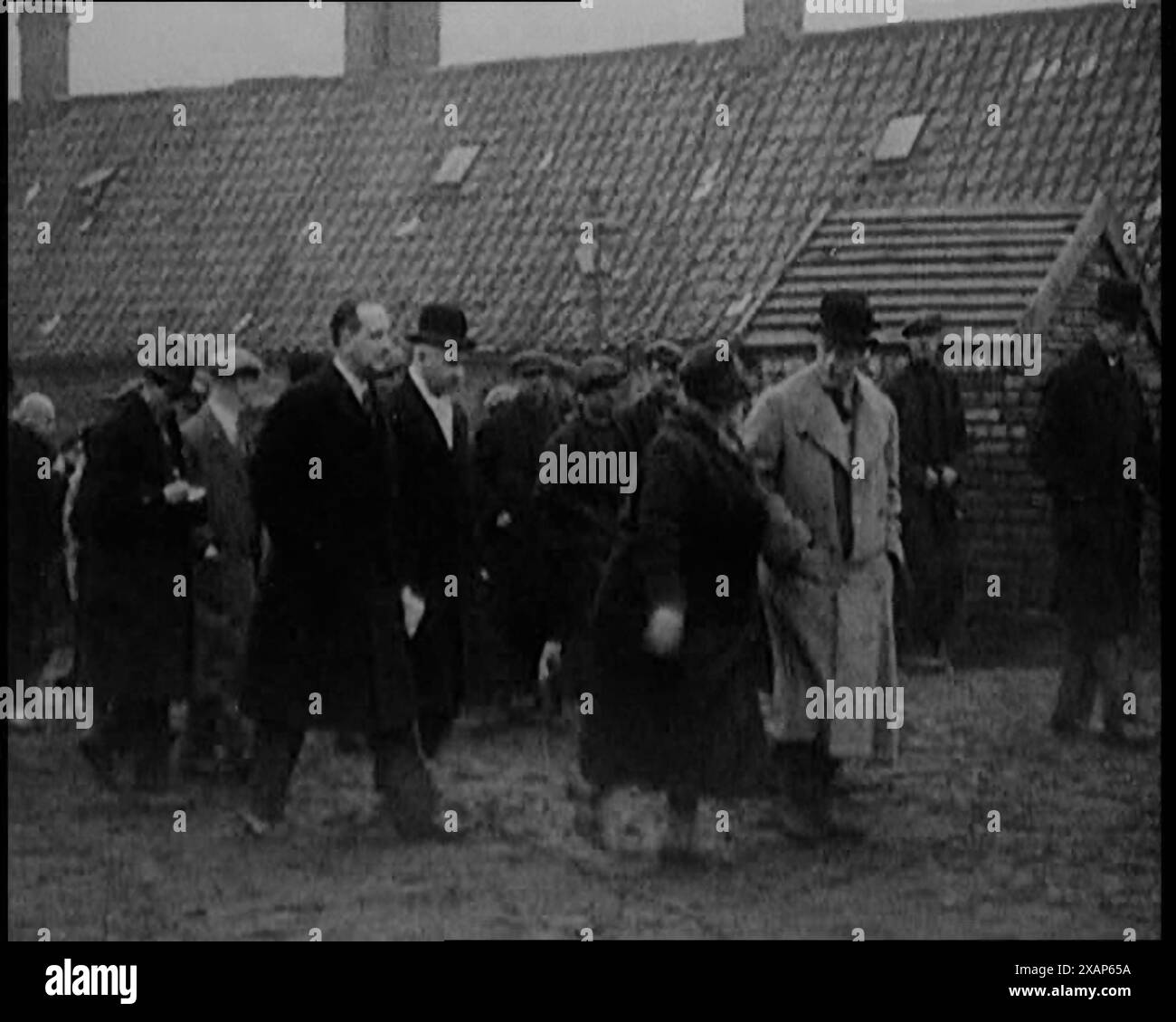 Prinz Edward, Prinz von Wales, der durch ein Dorf im Norden Englands spaziert, 1929. Die Große Depression. "In Großbritannien war der König [Georg V.] krank und rekonvaleszierend, also ging an seiner Stelle der Prinz von Wales [der zukünftige König Eduard VIII. Mit Bowler Hut] hinunter, um die schlimmsten Stellen zu besichtigen, um selbst zu sehen... "etwas muss getan werden", sagte er." Aus „Time to Remember – 1929 The Time of the House at Bognor“ – Reel 4; ein Dokumentarfilm über die Welt im Jahr 1929. Krankheit von König Georg V. &amp; wirtschaftliche Depression. Stockfoto