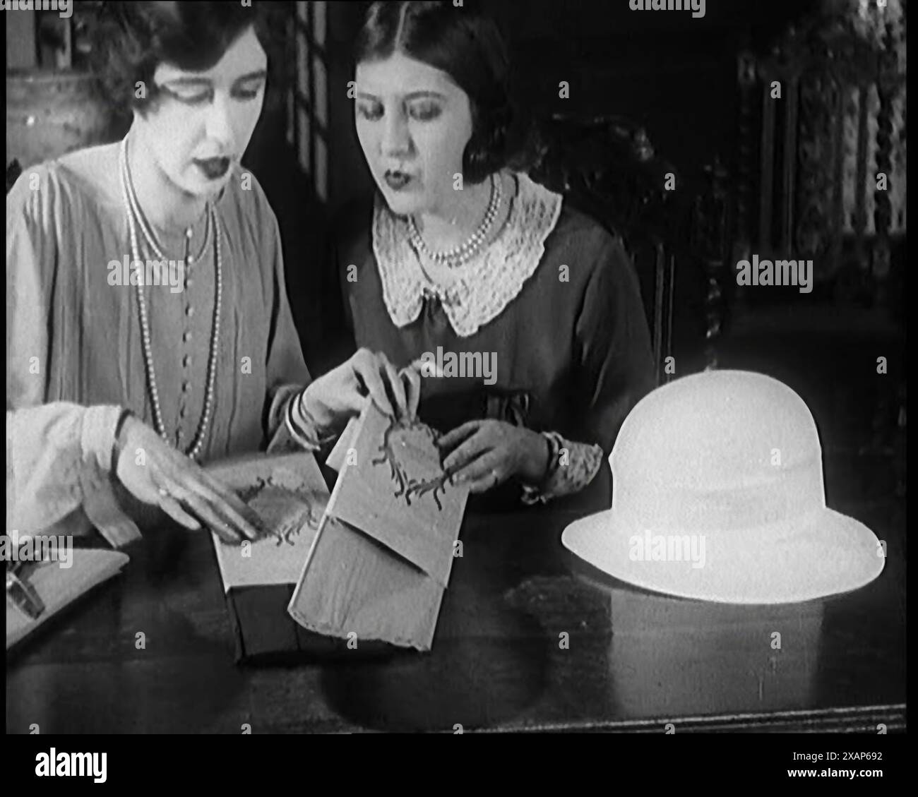 Zwei weibliche Zivilisten schneiden Blätter aus Papier, um einen Hut zu dekorieren, 1920er Jahre Aus „Time to Remember – Teenage Flapper“, 1920er Jahre (Rolle 1); ein Dkumentary über das Leben von Frauen in den 1920er Jahren – großartiger Kommentar von Joyce Grenfell. Stockfoto