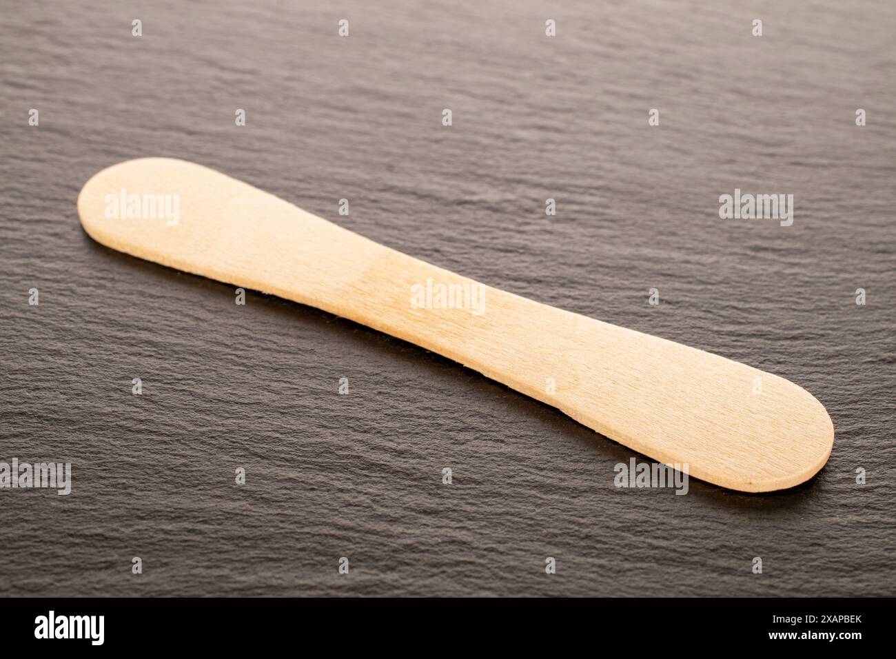 Ein hölzerner Eisstock, Makro, auf Schieferstein. Stockfoto