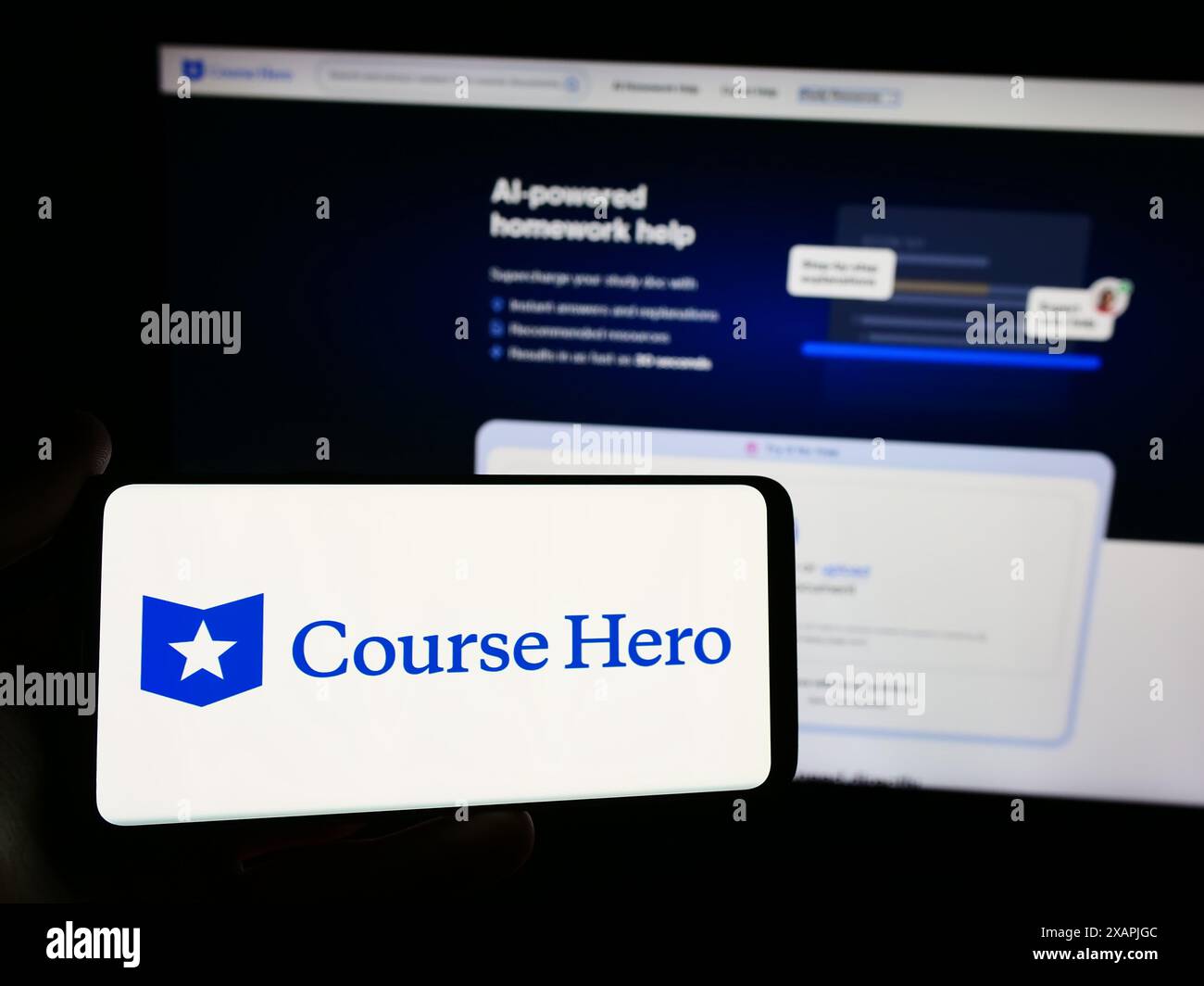 Person mit Smartphone und Logo des US-amerikanischen Bildungstechnologie-Unternehmens Course Hero vor der Website. Schwerpunkt auf dem Display des Telefons. Stockfoto