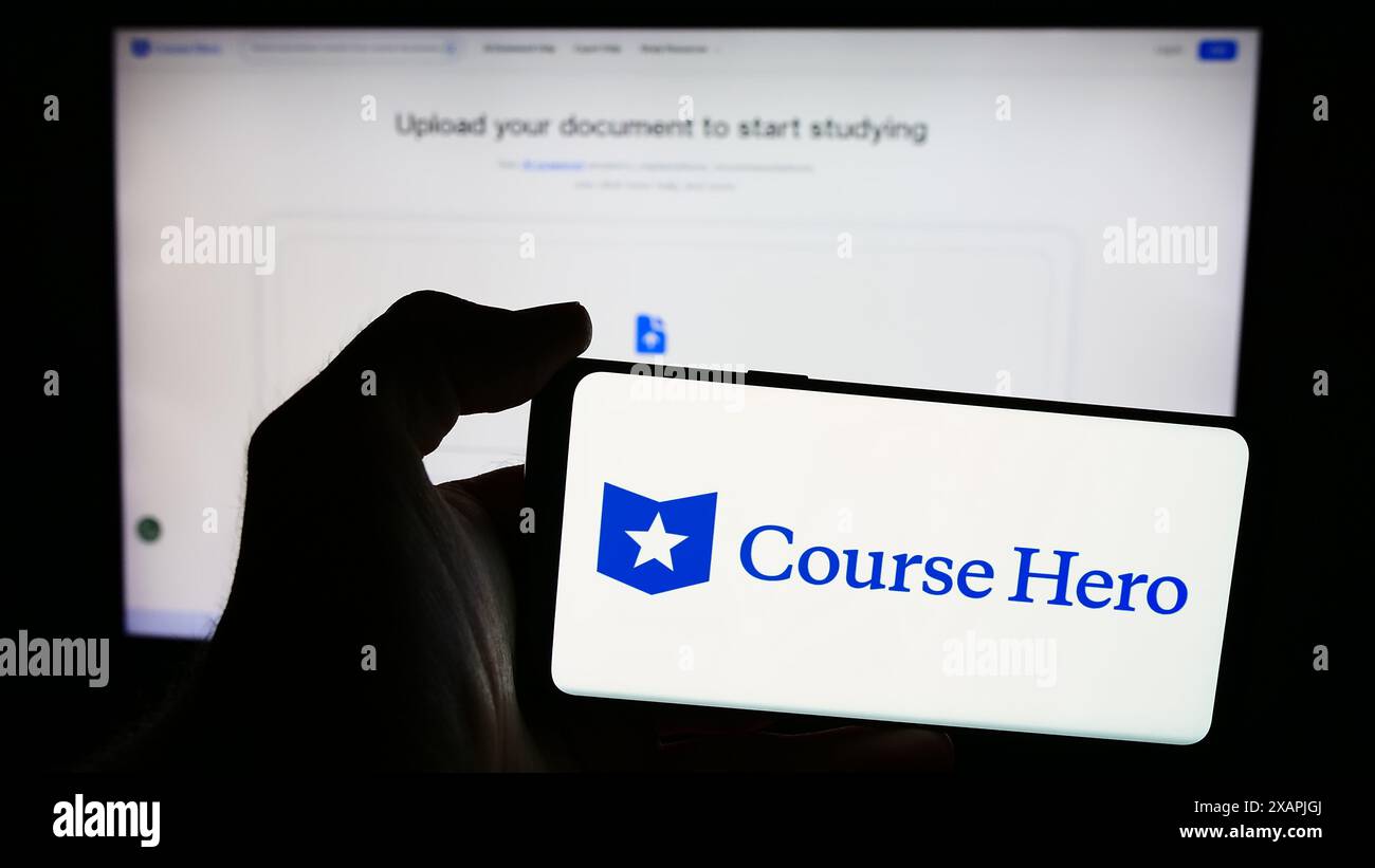 Person, die ein Mobiltelefon mit dem Logo des US-amerikanischen Unternehmens für Bildungstechnologie Course Hero vor der Business-Webseite hält. Schwerpunkt auf dem Display des Telefons. Stockfoto