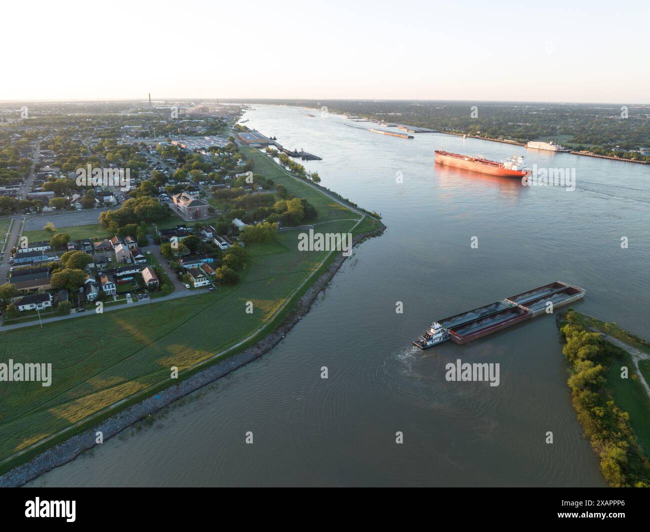 Aus der Vogelperspektive lässt ein Binnenschiff den Industriekanal in New Orleans' historischem 9th Ward verlassen und bei Sonnenaufgang in den Mississippi River eindringt. Stockfoto