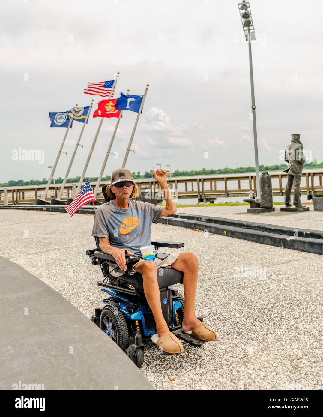 Charleston, South Carolina: Behinderter Veteran sitzt im Rollstuhl mit der Faust hoch mit den Fahnen im Navy Yard Museum von Charleston Stockfoto