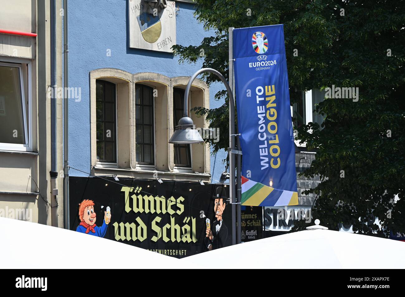 Flagge Fahne der UEFA Euro 2024 - Fussball Europameisterschaft mit der Aufschrift Willkommen in Köln dahinter zwei kölsche Originale: Tünnes und Schäl. *** Flagge der UEFA Euro 2024 Fußball-Europameisterschaft mit der Inschrift Willkommen in Köln dahinter zwei Kölner Originale Tünnes und Schäl Stockfoto