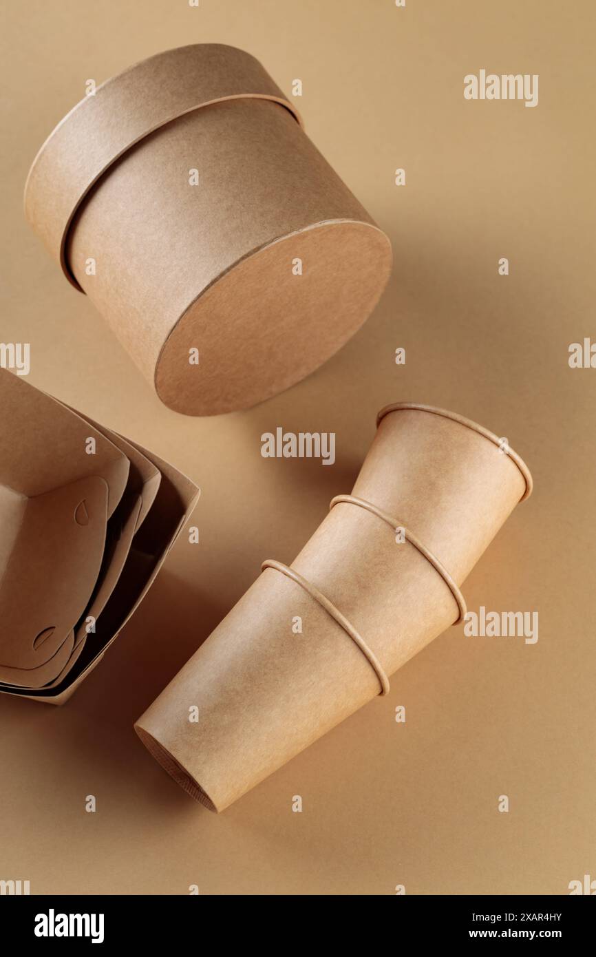 Einwegbecher und -Behälter aus Pappe auf beigem Hintergrund, Konzept der organischen Öko-Verpackung Stockfoto