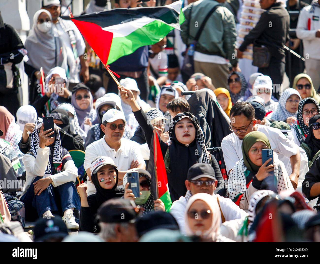 Bandung, Indonesien. Juni 2024. Während einer Solidaritätsaktion zur Verteidigung Palästinas in Bandung schwenkt eine Frau die palästinensische Flagge. (Foto von M Ardi Agusseptian/INA Photo Agency/SIPA USA) Credit: SIPA USA/Alamy Live News Stockfoto