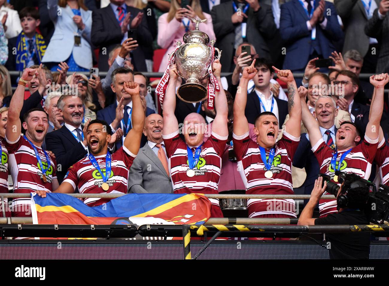 Liam Farrell (Mitte) von Wigan Warriors holt die Trophäe nach dem Sieg ...