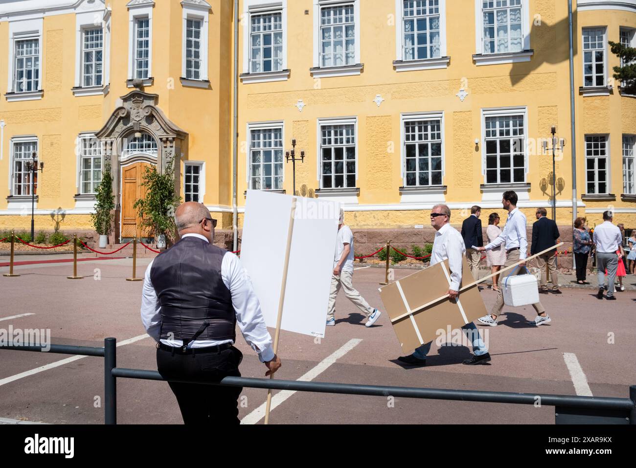 Familien treffen sich vor dem Hauptschulgebäude zum Åland-Abschlussfeiertag 2024 im Åland Lyceum (Ålands Gymnasium) in Mariehamn, Åland-Archipel, Ostsee, Finnland – an diesem Tag verlassen die Schüler die Schule zum letzten Mal. Im Rahmen dieser nordischen Tradition werden Plakate mit Babybildern der Absolventen aufgeklebt und die Studenten selbst tragen ihre Studentmössa im Matrosenstil und kleiden sich in Anzügen (Jungen) und weißen Kleidern (Mädchen). Foto: Rob Watkins. Stockfoto