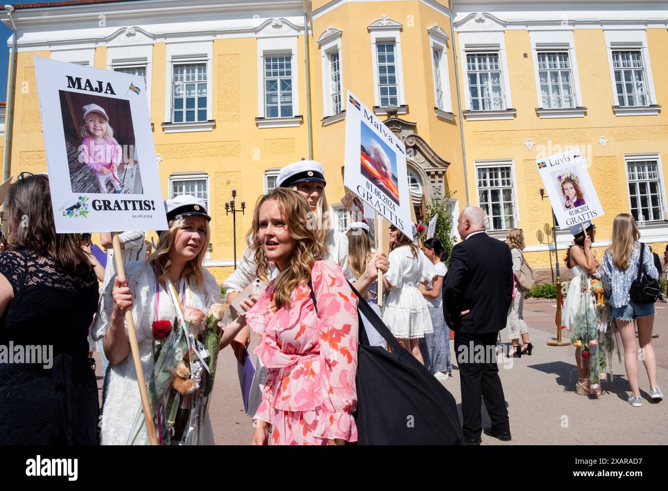 ABSCHLUSSFEIER, ÅLAND, FINNLAND: es ist eine chaotische Szene der Feierlichkeiten, wenn Familien und Freunde die neuen Absolventen vor dem Hauptschulgebäude treffen, um den Åland-Abschlussfeiertag 2024 im Åland Lyceum (Ålands Gymnasium) in Mariehamn, Åland-Archipel, Ostsee, Finnland – an diesem Tag verlassen die Schüler die Schule zum letzten Mal. Im Rahmen dieser nordischen Tradition werden Plakate mit Babybildern der Absolventen aufgeklebt und die Studenten selbst tragen ihre Studentmössa im Matrosenstil und kleiden sich in Anzügen (Jungen) und weißen Kleidern (Mädchen). Foto: Rob Watkins. Stockfoto