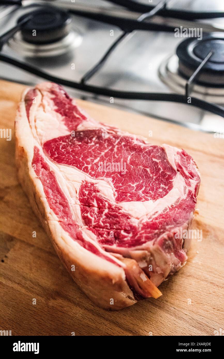 Ein großes, trocken gereiftes Rindersteak liegt auf einem Holzschneidebrett, das in Sevilla, Spanien, zubereitet werden kann. Stockfoto