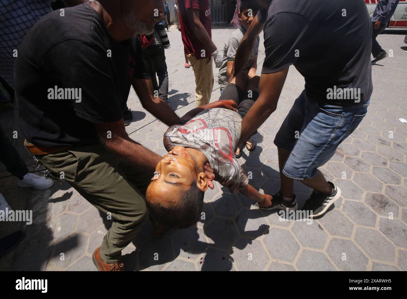 Deir Al Balah, Palästinensische Gebiete. Juni 2024. Palästinensische Männer tragen die Leiche eines kleinen Jungen, der bei gleichzeitigen israelischen Angriffen auf das Flüchtlingslager Nuseirat, das Flüchtlingslager al-Bureij und das Flüchtlingslager al-Maghazi getötet wurde. Israelische Spezialkräfte haben am Samstag vier Geiseln am helllichten Tag aus dem Flüchtlingsviertel Nuseirat im Zentrum des Gazastreifens gerettet, nachdem sie 246 Tage in Gefangenschaft waren. Quelle: Omar Naaman/dpa/Alamy Live News Stockfoto