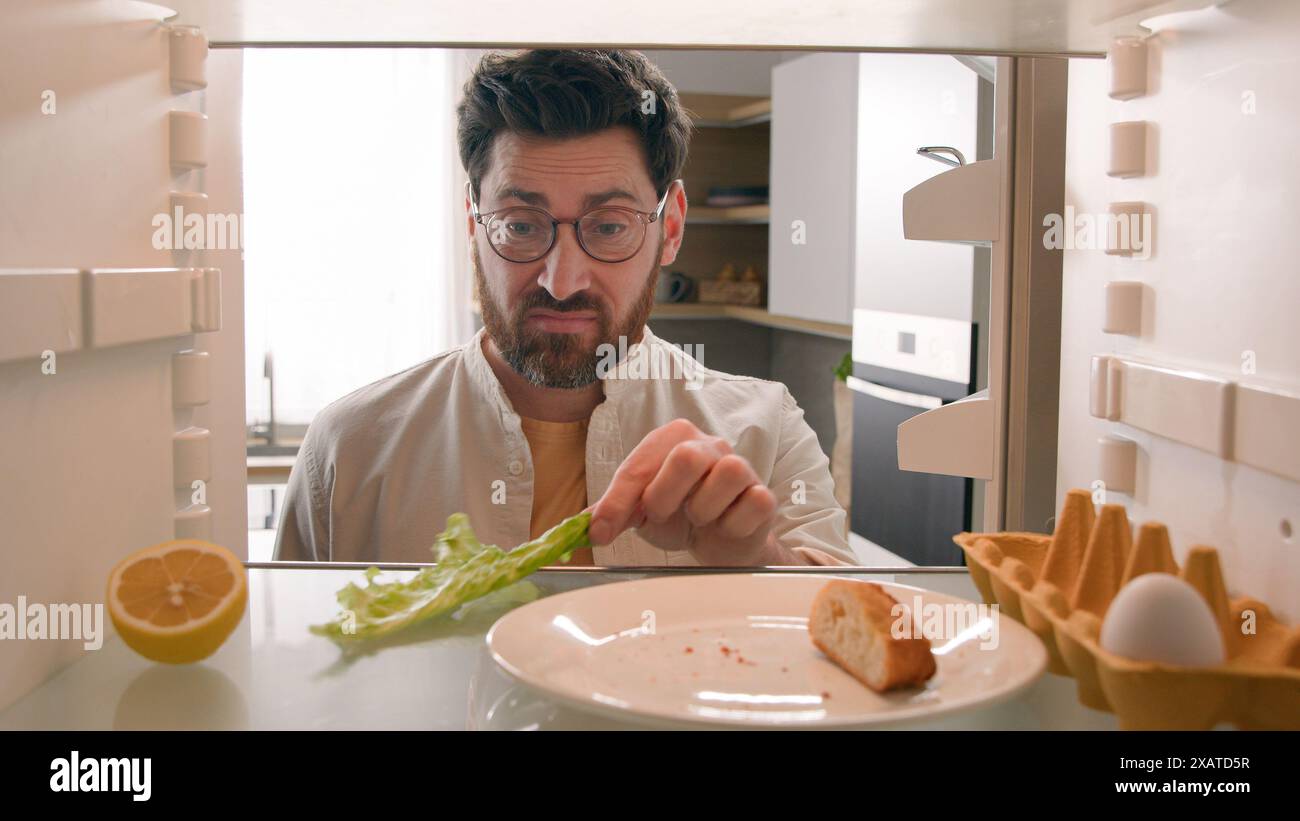 Blickwinkel von innen Kühlschrank POV Kaukasischer Erwachsener Hausbesitzer öffnen Kühlschranktür Küche riecht schrecklich riechender Kerl schlechtes Aroma Stockfoto