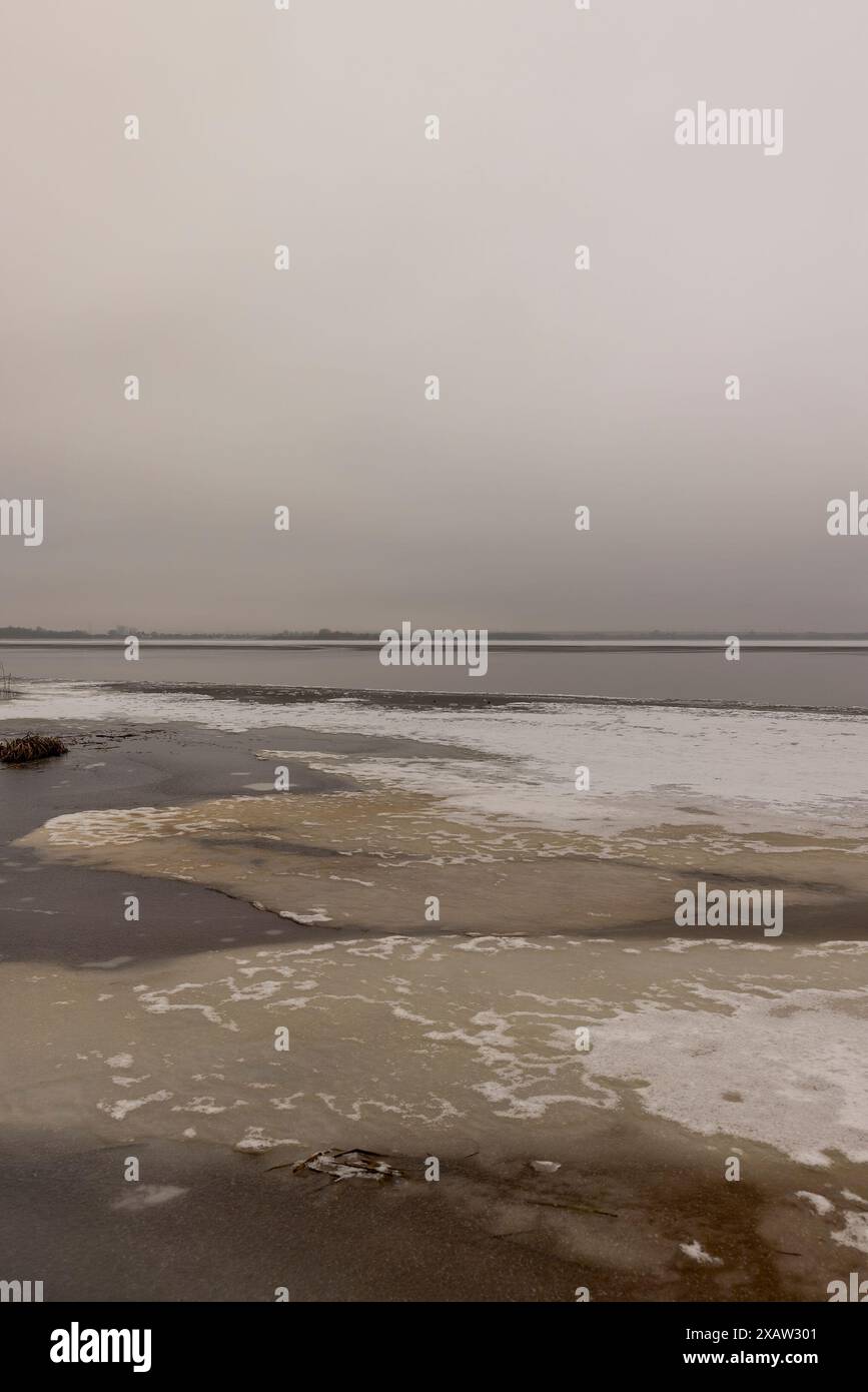 Gefrorener See im Winter bei bewölktem Wetter, Eis auf dem See bei Frost Stockfoto