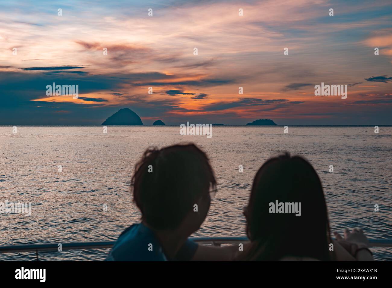 Silhouette von zwei Personen mit Blick auf das Meer mit Sonnenuntergang im Hintergrund Stockfoto