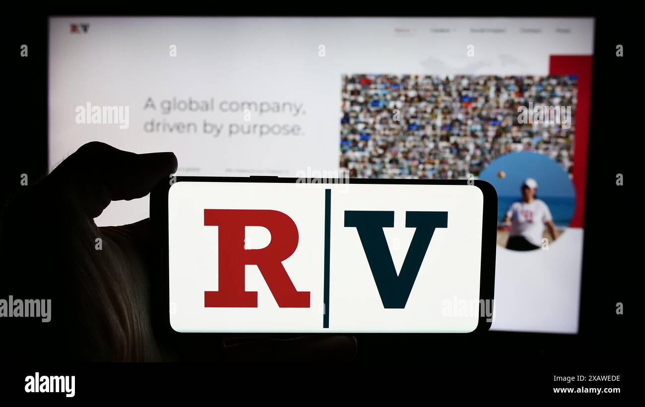 Person, die ein Mobiltelefon mit dem Logo des US-Medienunternehmens Red Ventures LLC vor der Website des Unternehmens hält. Schwerpunkt auf dem Display des Telefons. Stockfoto